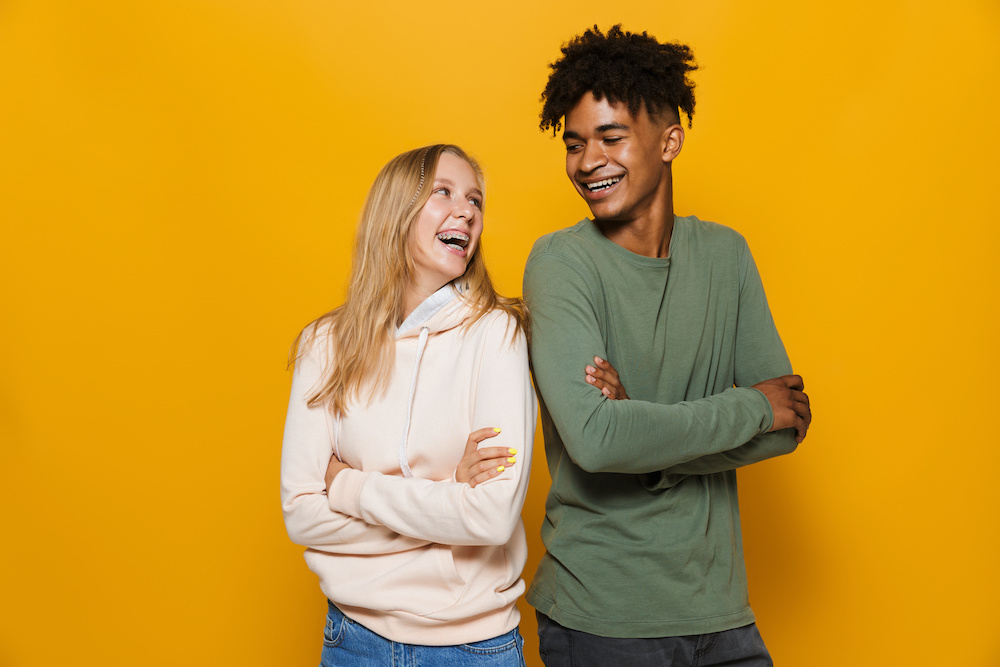Photo of teenage people man and woman 16-18 with dental braces smiling, isolated over yellow background Here's what you can expect when you get braces in Charleston SC