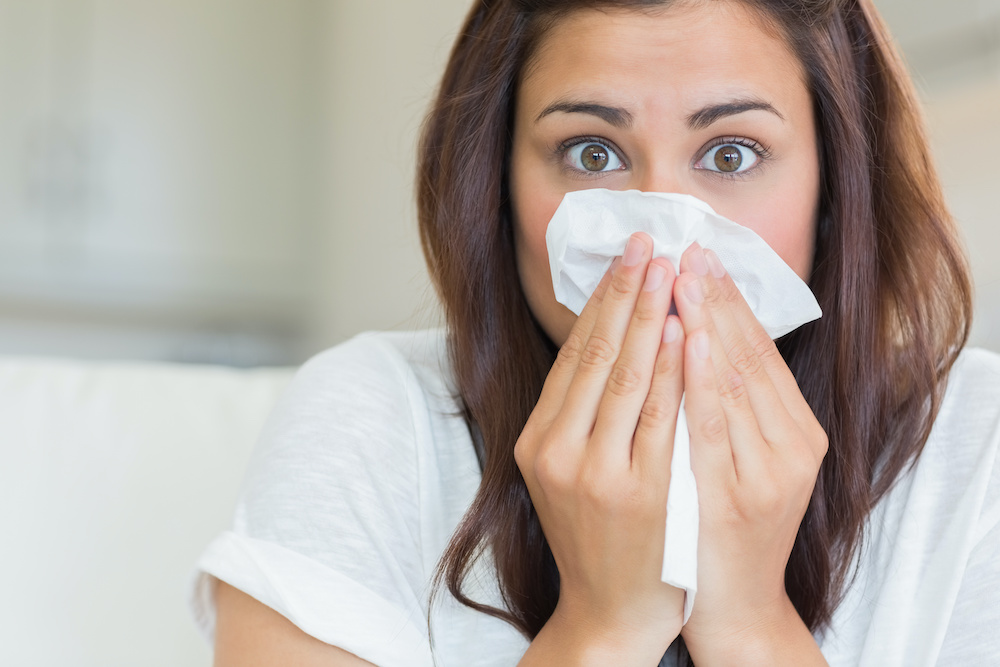 Brunette sneezing into tissue Learn about allergies and braces from the best orthodontist in Charleston SC